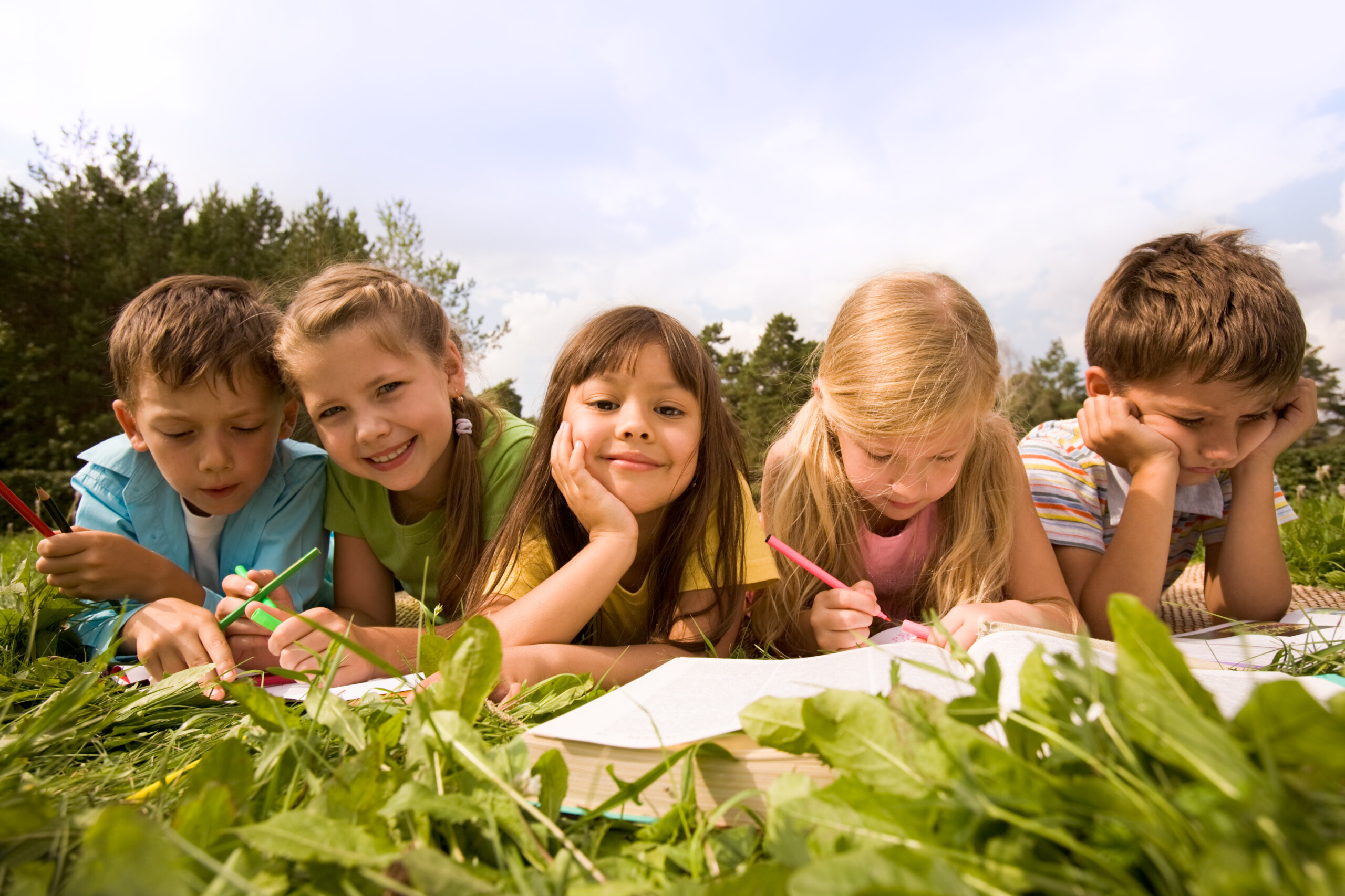 Kinder liegen auf der Wiese und lesen