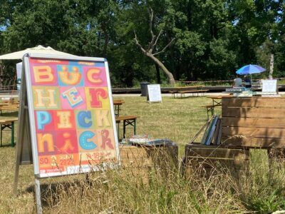 Aufsteller mit Bücherpicknickplakat steht auf Wiese