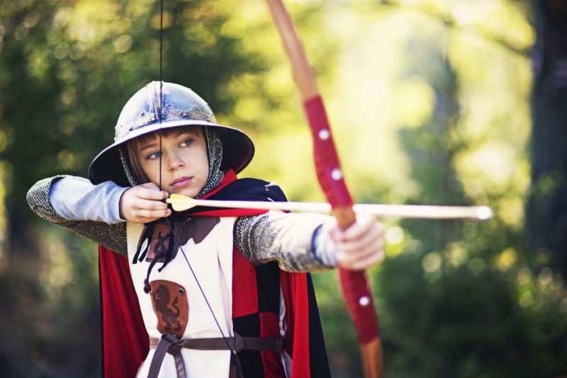 Mädchen in Ritterkostüm bogenschießend