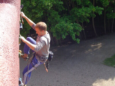 Mann klettert an Boulderwand hoch