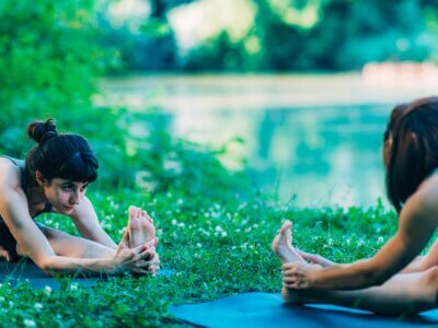 Zwei Frauen machen Yoga auf einer Wiese